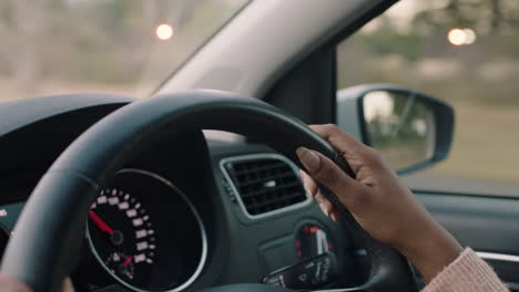 woman driving car with hands on steering wheel to control vehicle in city travelling on the road at rush hour to destination