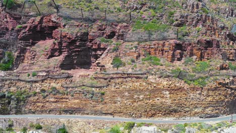 an aerial shot of a bicyclist traveling on a dangerous narrow mountain road along the ocean chapmans peak road near cape town south africa