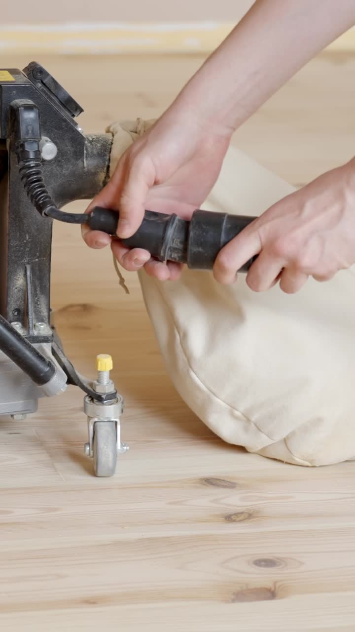 Hands plug in and connect power to tool on uneven wood floor edge during renovation, vertical