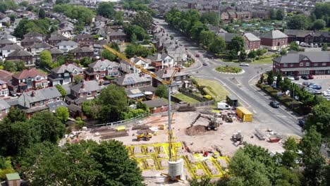 grúa alta estableciendo cimientos de edificios en el vecindario de la ciudad británica vista aérea en órbita por encima de los techos de las casas suburbanas