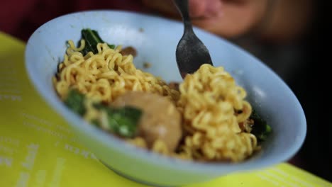 shot of someone eating their indonesian food and playing with their noodles