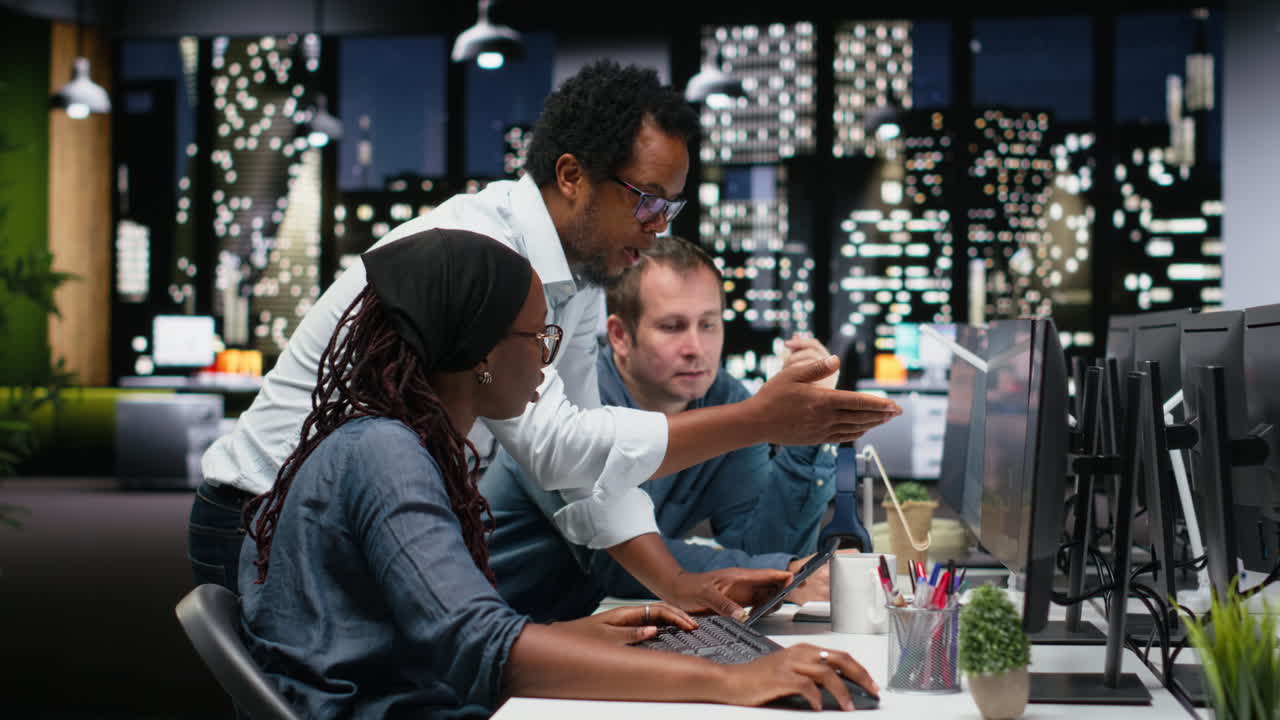 Diverse Business Team Collaborating on Computer in Modern Office at Night