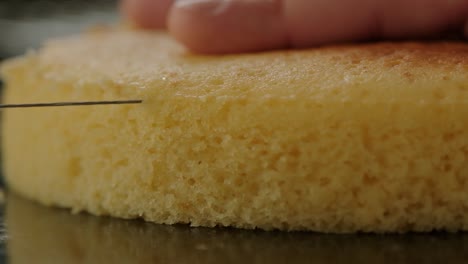 close-up of cutting the top off a sponge cake to make a flat layer