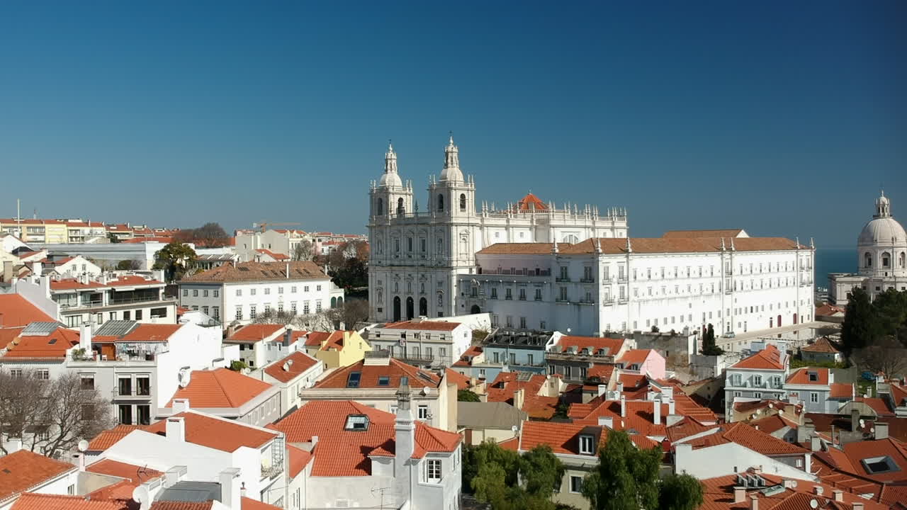 Carrellata aerea sopra i tetti di Alfama verso una chiesa imponente, Lisbona, Portogallo