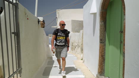 un hombre camina por un callejón de una isla griega en un día soleado