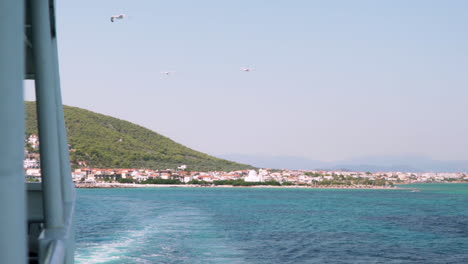 Slow-motion-of-ferry-board-departing-from-Agistri-island,-Argosaronikos,-Greece,-seagulls-follow-the-trail-of-the-ship-120fps