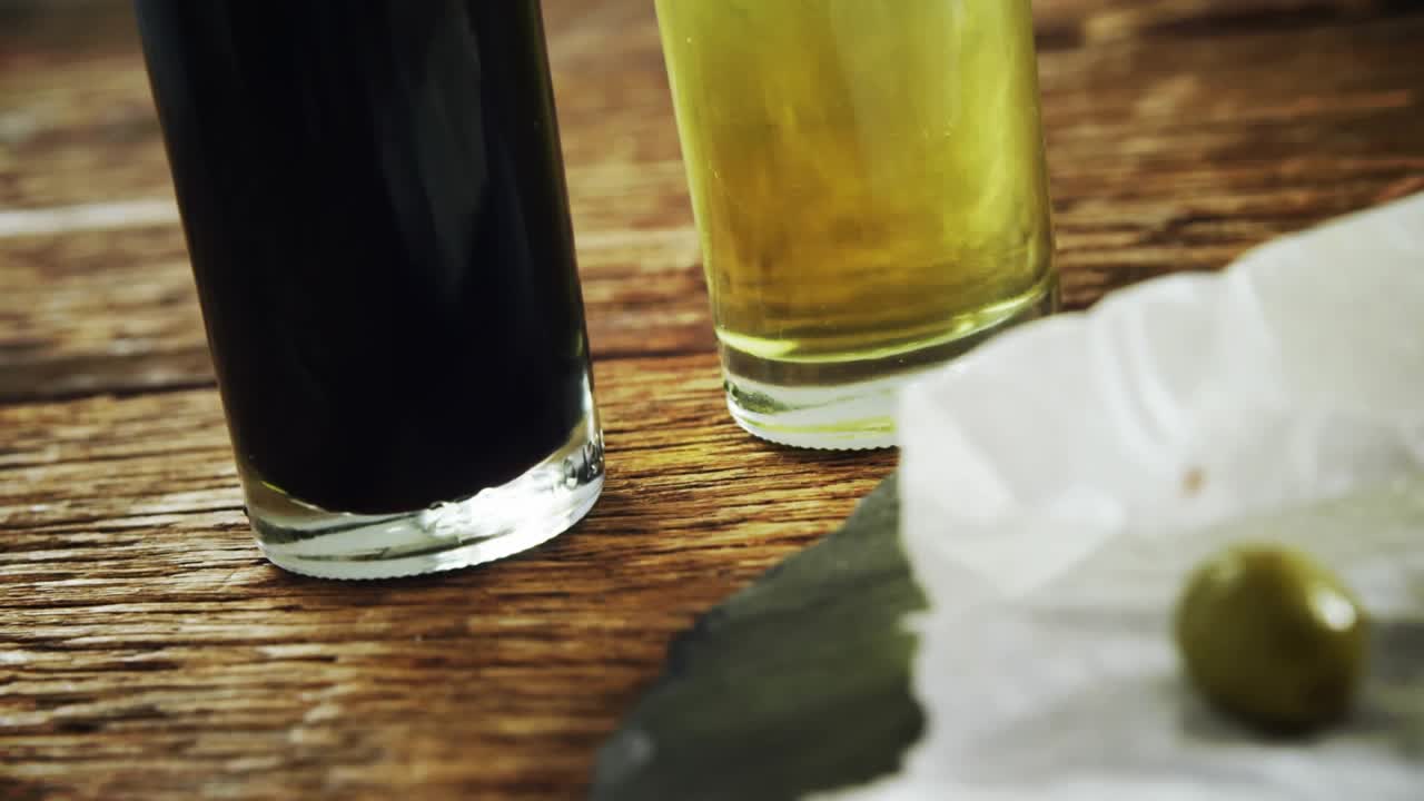 Gold confetti falling, camera panning right, zooming, olives rolling toward bread, showing pile