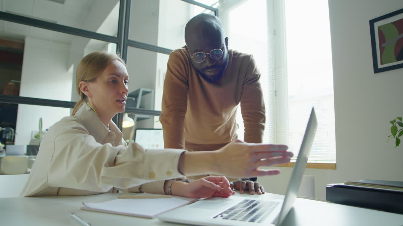 Businesswoman Discussing Project on Laptop with Male Colleague