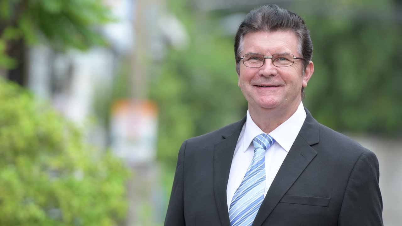 Glücklicher, gutaussehender älterer Geschäftsmann auf der Straße im Freien.