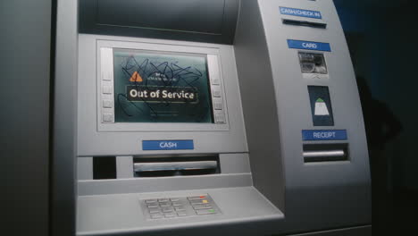unrecognizable person marking atm screen with graffiti with marker. vandal causing property damage, vandalizing out of service cash machine with illegal graffiti. vandalism of public banking equipment