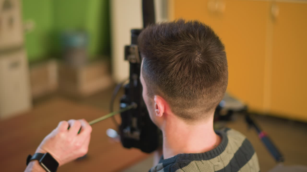 TV technician adjusting camera lens, setting up equipment, working with microphone, lights, preparing for video shoot in home studio or media production setup