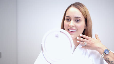 beautiful slow motion shot of a young beautiful woman happily checking her beauty treatment results she received at a dermatology clinic with beautiful skin