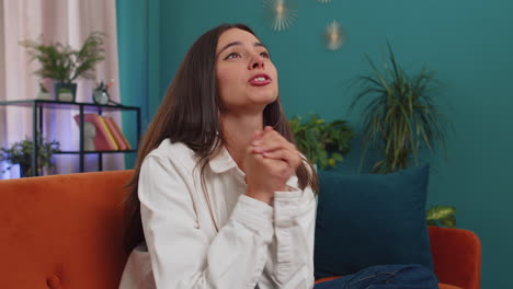 young woman praying sincerely with folded arms asking god for help, begging apology, making a wish