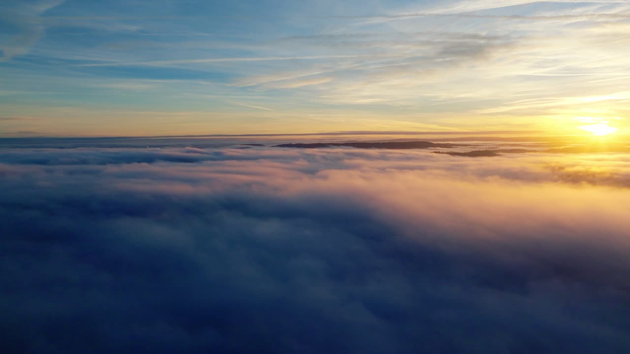 A wide sea of clouds glows orange and blue under a painted evening sky.