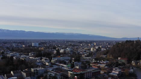 aerial flying over kutaisi city with snowy mountains and river