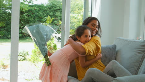 daughter giving mother bunch of flowers for birthday or mothers day at home