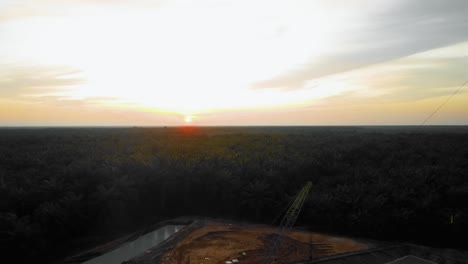 Cinematic-4K-Drone-Footage-of-Onshore-Drilling-Rig-equipment-structure-for-oil-exploration-and-exploitation-in-the-middle-of-jungle-surrounded-by-palm-oil-trees-during-sunset-and-high-oil-price