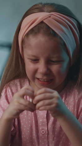 assiduous long haired little girl with pink headband tries to open pill bottle to cure younger brother in semi-dark room at home extreme close view slow motion