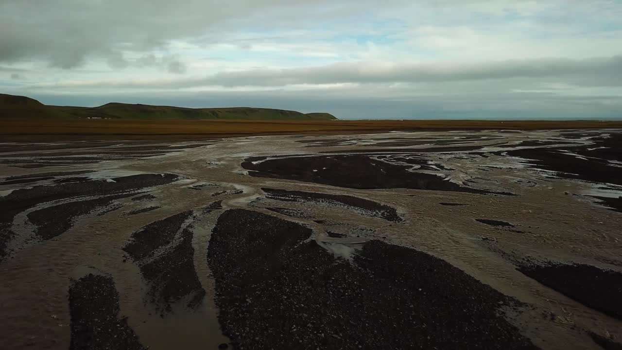 Aerial landscape view of a glacier river with many branches flowing in a valley, on dark sand, in Iceland