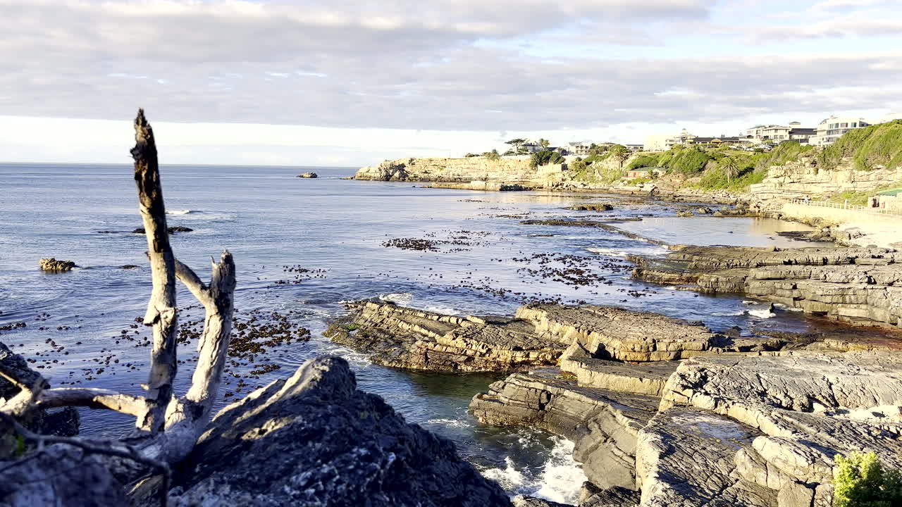 Rolig morgenudsigt fra kystklippen ved Hermanus kystlinje med marint tidevandsbassin.