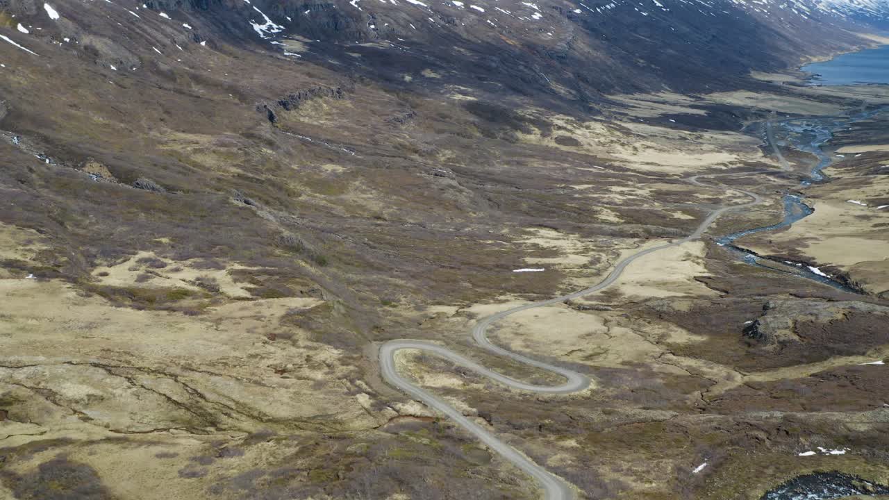 Droneflyvning over snoet vej ind i dal og fjord på Island.