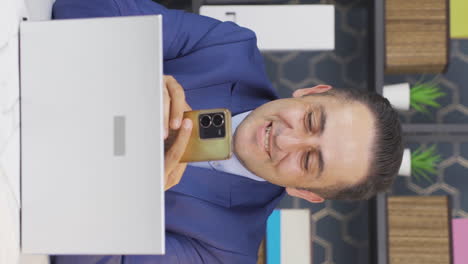 Vertical-video-of-Happy-businessman-using-phone-laughing.