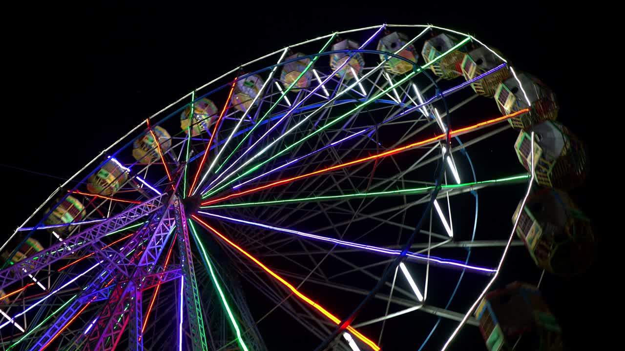 검은 밤의 배경에서 회전하는 밝은 다채로운 페리스 의 4k 영상.