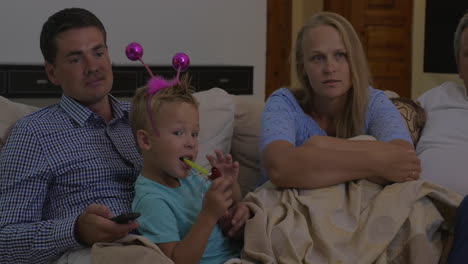 parents and son watching tv at home