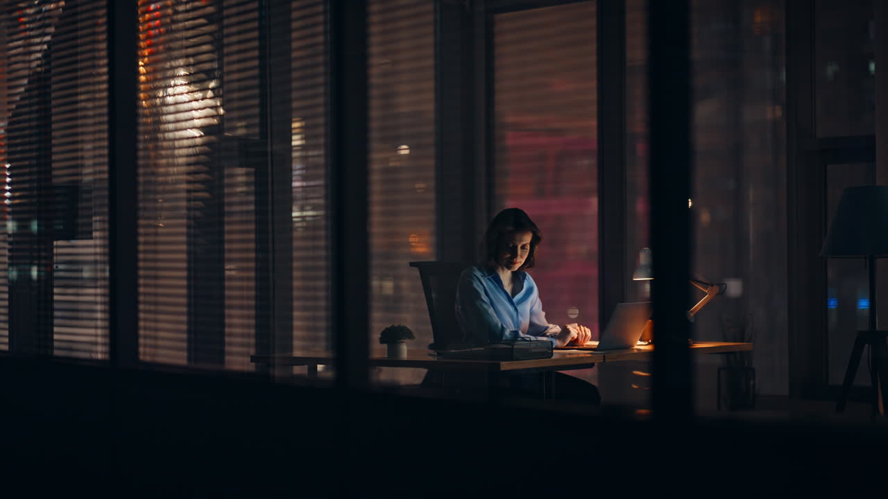 Dipendente notturna che lavora in una startup in un ufficio aziendale buio. Donna laboriosa impegnata