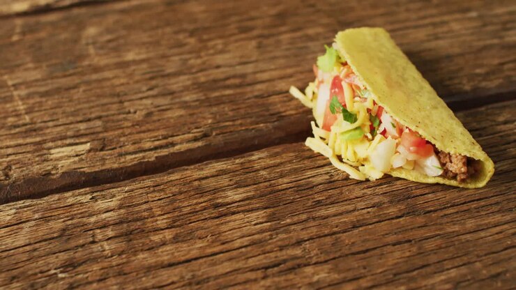 Video of freshly prepared tacos lying on wooden background
