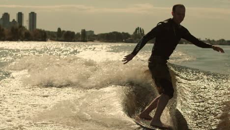 surfer riding wave on wakeboard in slow motion. man surfing at sunset