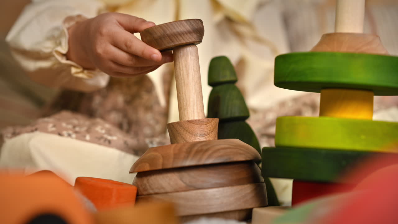 Little girl's hands playing with a wooden stacking jug. Ecological and sustainability concept