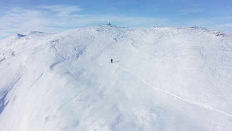 esquiador sobreviviendo al frío de hamlagro bergsdalen noruega - subiendo una colina nevada para llegar a la cima de la montaña en un día despejado con cielo azul