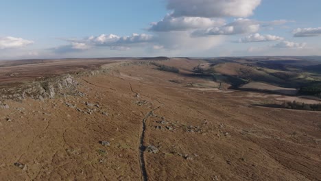 aerial drone footage showing beautiful open moorland with rock formations, fields, trees, trails and a trig point