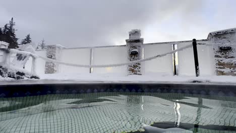 hot steam rising from a hot pool in halcyon hot springs british columbia with a bright yellow sunset coming through the frost covered glass