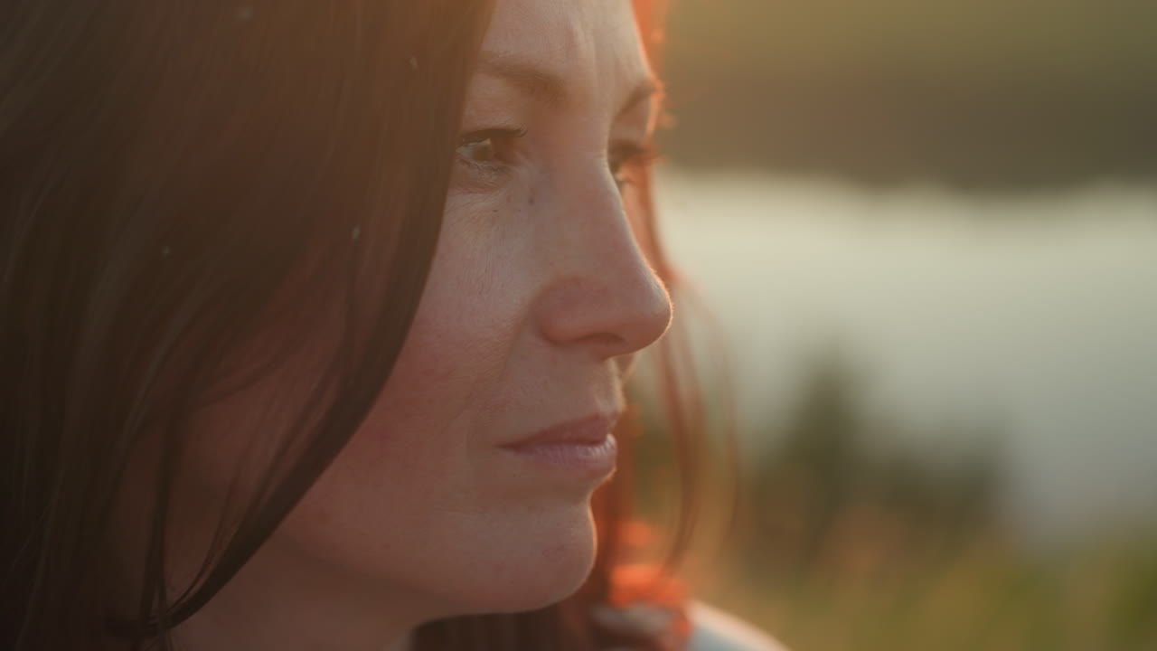 Close up of fair skin woman with closed eyes focusing calmly as insects fly near her face in golden sunlight, soft bokeh background showing warm natural light and subtle facial expression of serenity