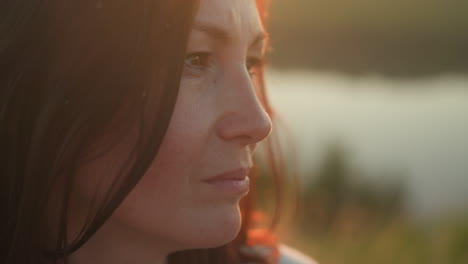 close up of fair skin woman with closed eyes focusing calmly as insects fly near her face in golden sunlight, soft bokeh background showing warm natural light and subtle facial expression of serenity