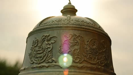 sunlight reflecting off a large bronze bell highlights its ornate carvings and intricate details, showcasing cultural significance