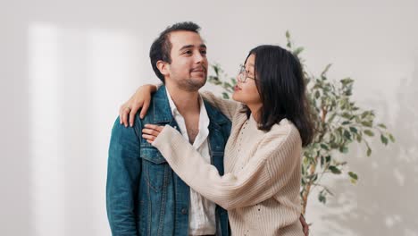 a young married couple stands in an empty purchased apartment, embrace each other, enjoy the move, laugh, in love are happy, talk