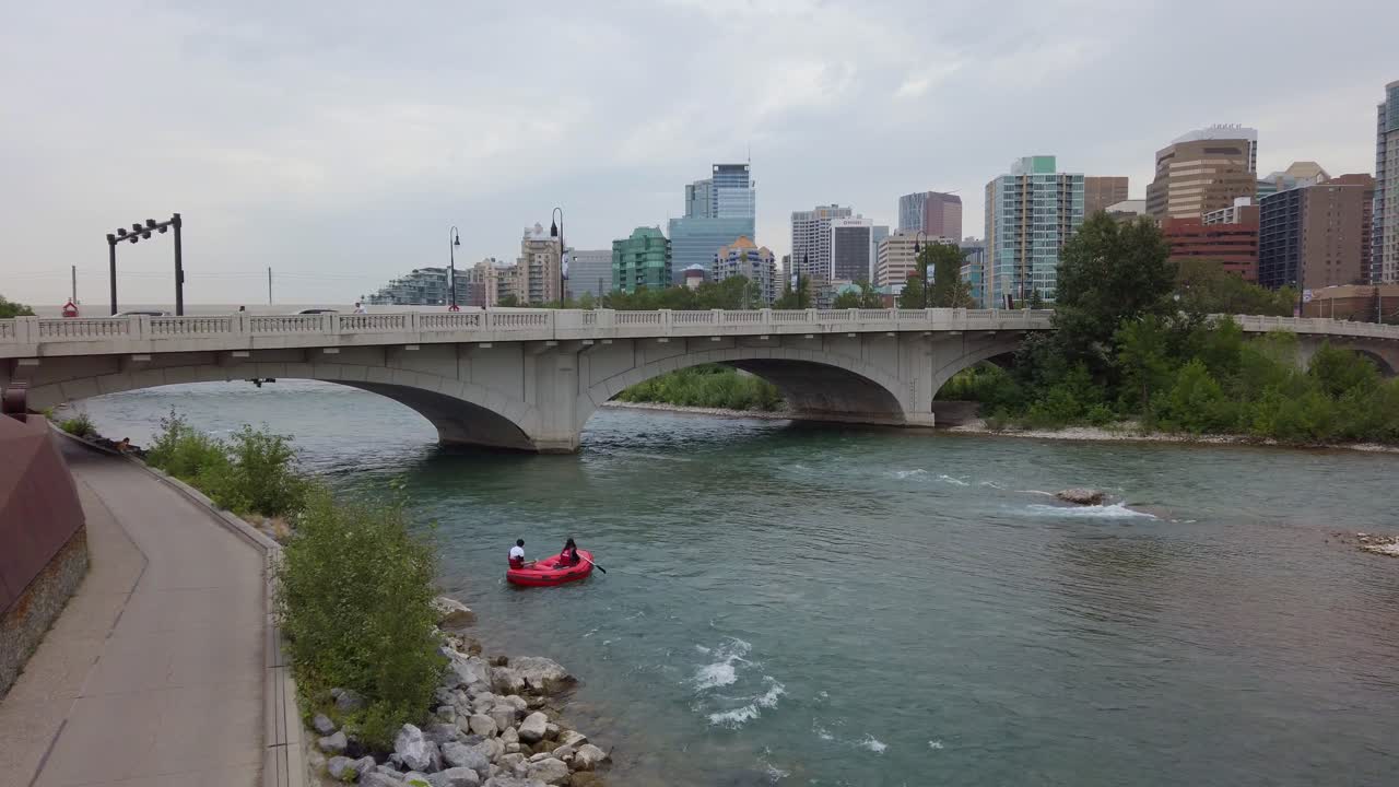 Coppia in barca nel fiume della città, panoramica del ponte e dello skyline in una giornata nuvolosa, con il Monumento Memorial Drive a Calgary, Canada.