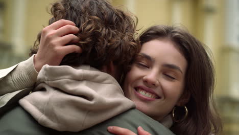 romantic couple hugging in city center. woman touching man hair on urban street.