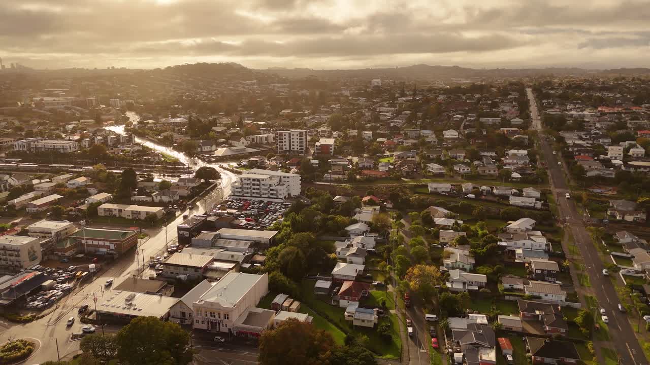 Auckland City with cars on street during golden Sunset. Aerial wide shot. Houses and homes. Cloudy sky in summer. Suburb residential area in New Zealand.