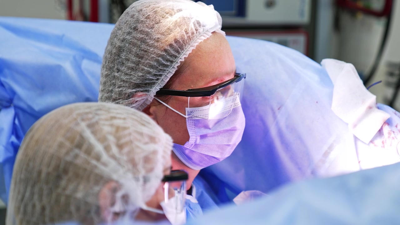 Volti di due chirurghi donne che indossano cappellini, maschere e occhiali protettivi. Primo piano. Medici concentrati sull'intervento.
