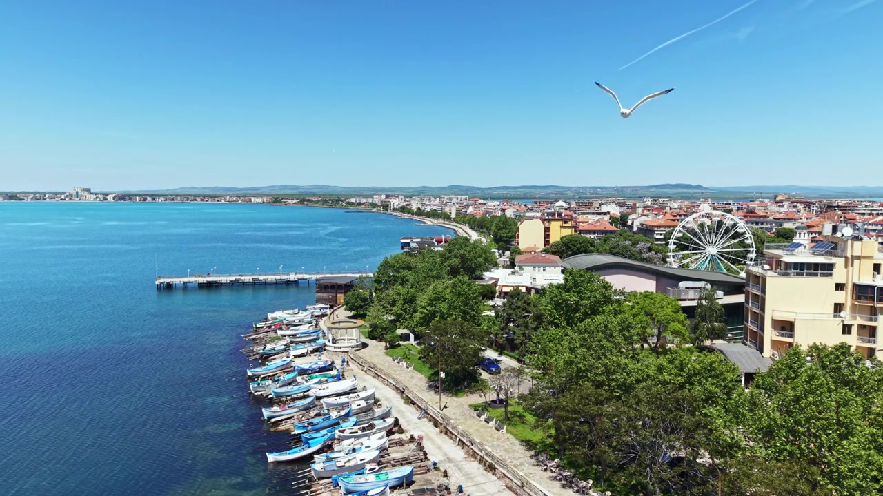 Vista de uma área à beira-mar com barcos e edifícios durante um dia claro em uma cidade costeira.