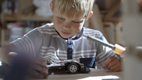 Kind-Baut-In-Der-Bastelwerkstatt-Ein-Elektroauto