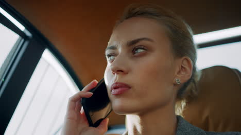 Closeup-focused-business-woman-discussing-business-on-mobile-phone-at-car