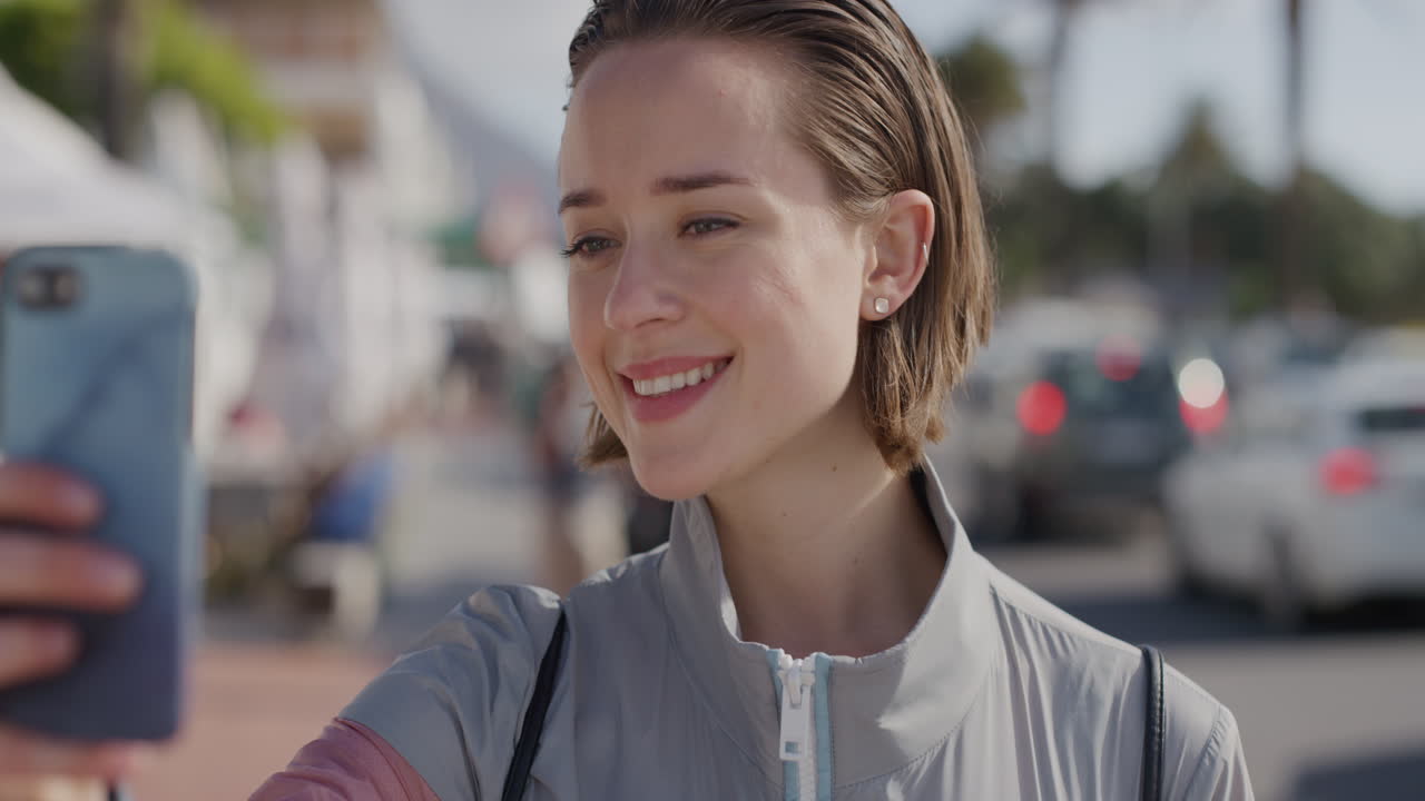 portrait of young caucasian woman taking selfie photo smiling using smartphone camera technology enjoying summer vacation on vibrant urban beachfront