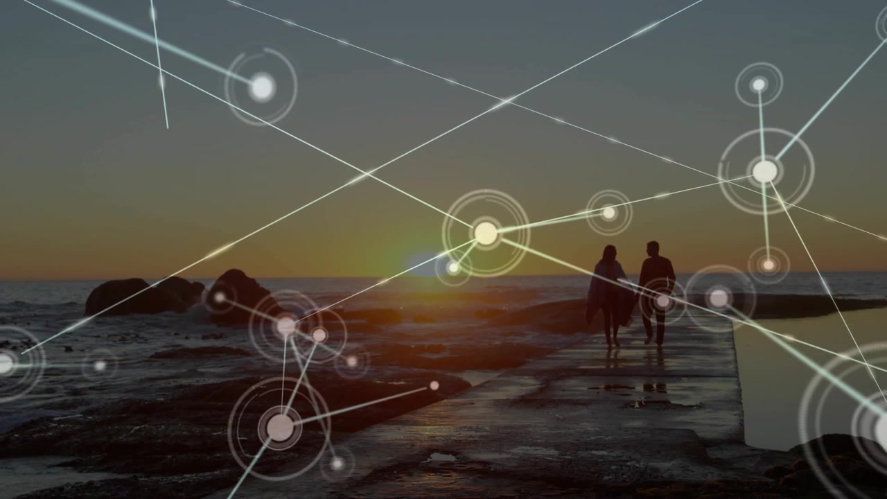 Vertical video: Couple in coats walking jetty to sun, sinking sun sparking net overlay, copy space