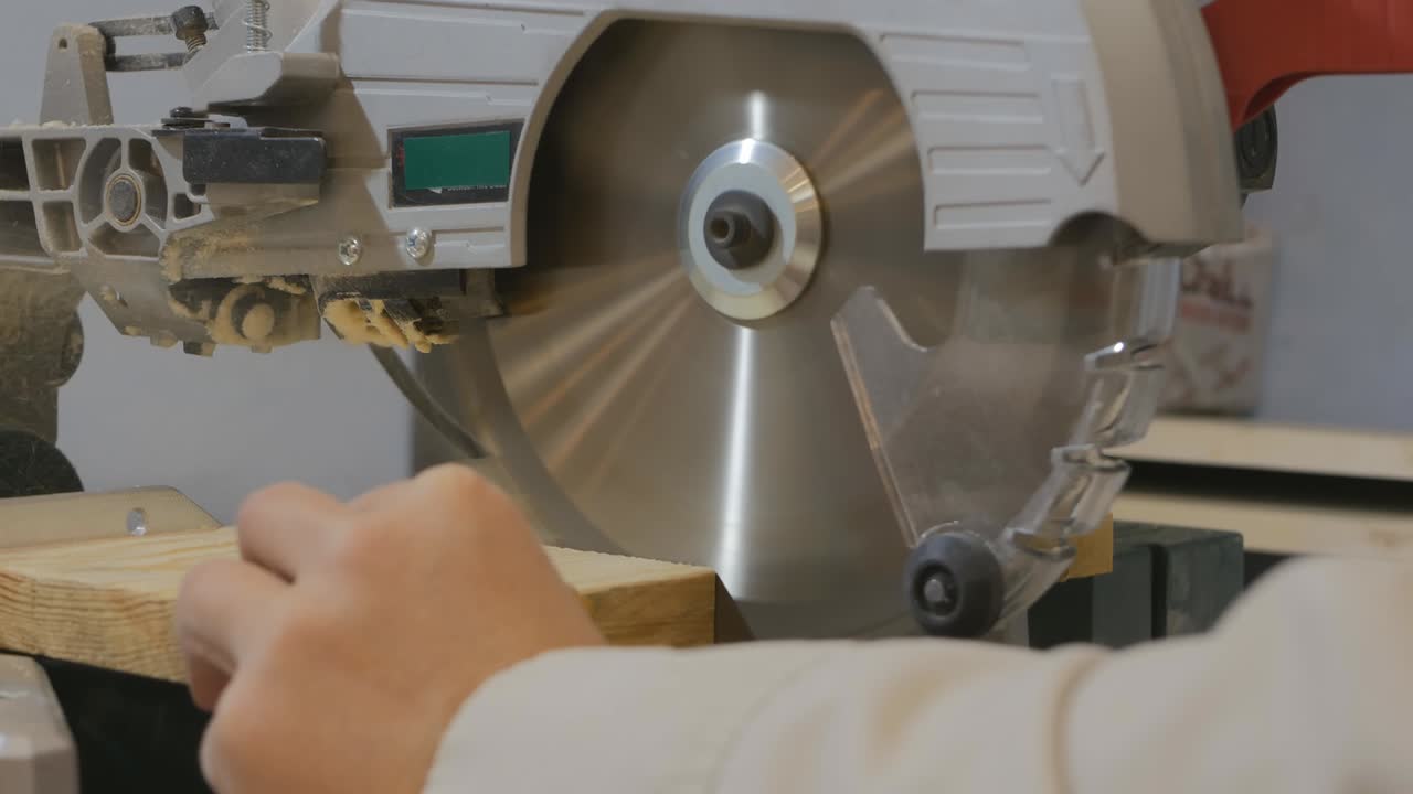 крупный план круговой митерной пилы опускает и отрезает материал. плотница женщина, работающая с пилой. мастерская для работы с деревянными изделиями. 4k
