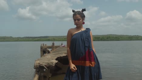 cinematic shot of an indian fashion model posing in a blue red and orange sustainable fashion dress in goa india close to the water in slow motion, slomo